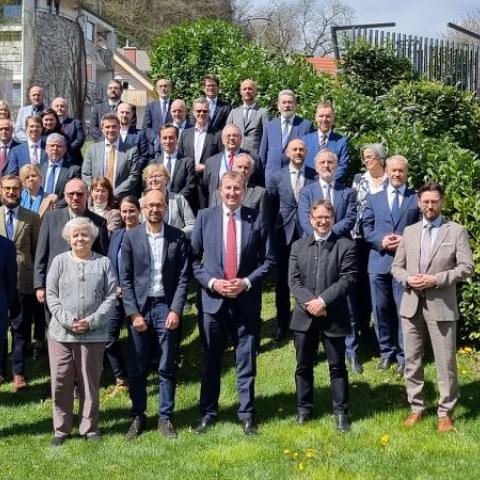 All participants of the meeting are standing in front of a building.