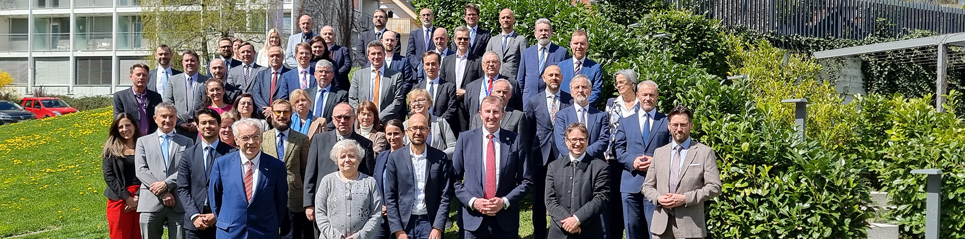 All participants of the meeting are standing in front of a building.